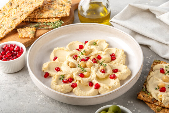 Creamy Hummus With Pomegranate and Crunchy Seed Crackers Served With Olives and Olive Oil