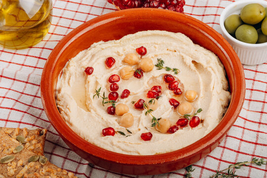 Creamy Hummus Bowl With Pomegranate Seeds, Chickpeas, Olive Oil and Rustic Bread