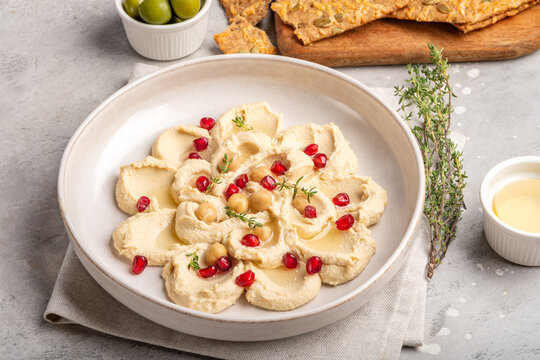Creamy Hummus With Pomegranate and Crunchy Seed Crackers Served With Olives and Olive Oil