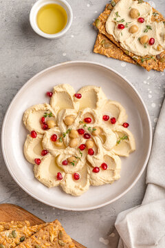 Creamy Hummus With Pomegranate and Crunchy Seed Crackers Served With Olives and Olive Oil
