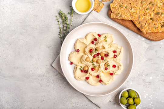 Creamy Hummus With Pomegranate and Crunchy Seed Crackers Served With Olives and Olive Oil