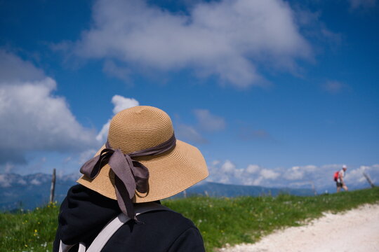 Back view of a female traveler with sun hat looking at mountain landscape