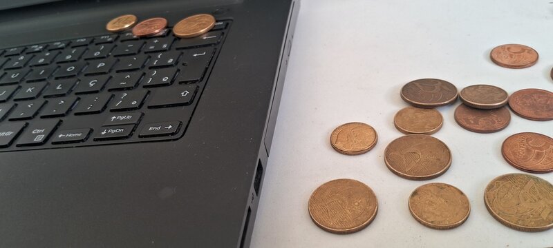 Brazilian centavo coins placed next to a black laptop keyboard surface