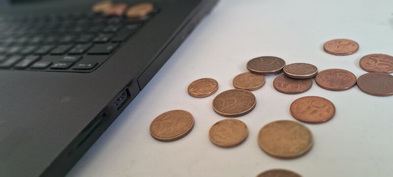 Shiny metallic Brazilian centavo coins resting beside a black laptop