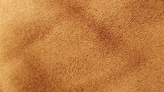 Texture of soft brown suede material, showing detailed velvety structure, perfect for premium leather goods background or textile design.