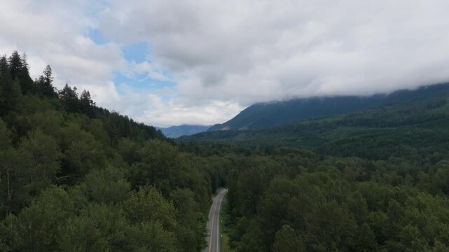 Winding Road Through Lush Mountain Forests of British Columbia Under a Cloudy Sky