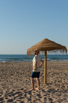 Vertical Hispanic man relaxing on sunny beach by the sea