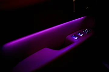 person relaxing in luxury car interior using phone with casual vibe and purple ambient lighting from passenger side view in vehicle with leather seats and wooden dashboard. © Евгений Вершинин