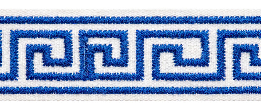 Greek key embroidery border ribbon with blue meander pattern on white fabric trim, classic Mediterranean geometric ornament design element isolated on black background for textile fashion crafts.