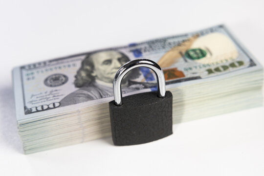 Closed black padlock on stack of US dollar banknotes isolated on white background