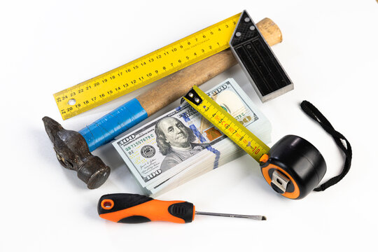 Stack of US dollar banknotes surrounded by construction tools on white background