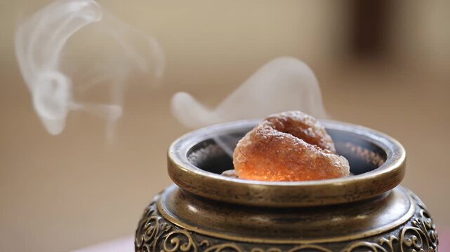 Close up of frankincense burning in a decorative censer, releasing aromatic smoke