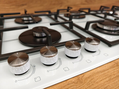 Close up on control knobs of a white built in gas cooker on display in a construction superstore for home kitchen use