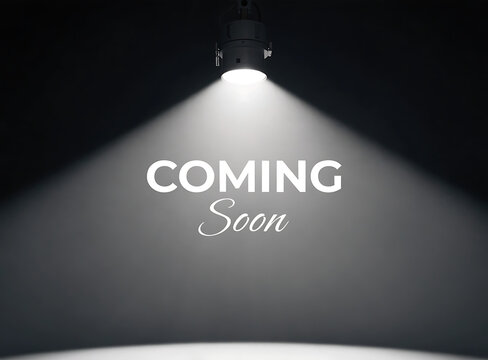 A spotlight shines on a coming soon announcement in a dark room