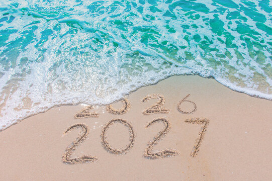 Message Year 2026 replaced by 2027 text written on beach sand background. Good bye 2026 - 2027 happy New Year coming concept.  top view.