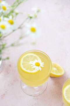 Traditional Italian limoncello or lemon liqueur. Outdoor table setting with flowers, with lemon slice, daisy flower, glass of lemonade, lemon halves, with glass, lemon texture, from a top-down