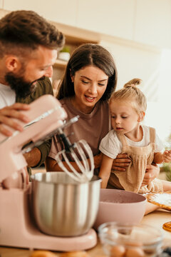 Family with child baking together using kitchen mixer