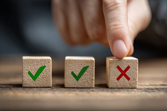 A hand selects a block with a red "X" between blocks with green check marks on a wood surface