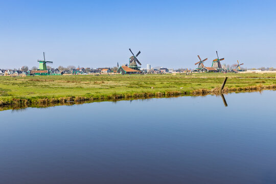 Zaandam, Netherlands. Wide angle view of traditional Dutch windmills along the horizon, perfectly reflected in the calm waters of a polder ditch.