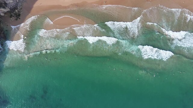 Aerial boom up shot reveals the stunning blue-green Praia do Beliche beach near Sagres, Portugal. This remote coastline features dramatic cliffs, golden sand, and crashing ocean waves.