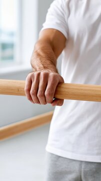 A hand holds onto a rehabilitation parallel bar, showing tension and effort during a therapy session in a neutral setting