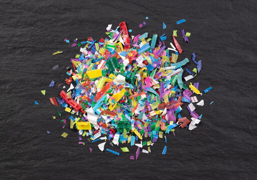 Heap of microplastic on black background, close up, top view 