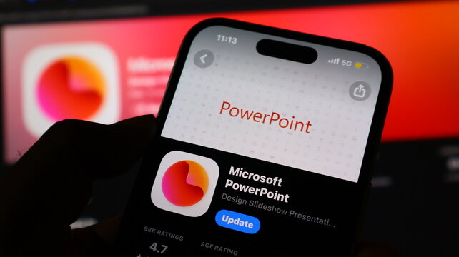 Hand holding smartphone with Microsoft PowerPoint app on screen