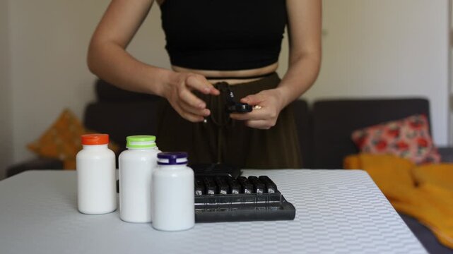Perception of health shifts as person relies on daily supplements and organizes pills into dispenser showing dependence on vitamins illusion of control and modern obsession with optimizing body