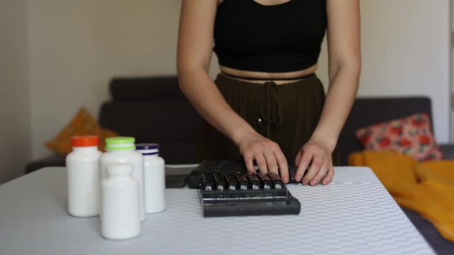 Rising trend of supplement overuse as person organizes multiple pills into daily container reflecting modern pressure to optimize health constant tracking and reliance on routines