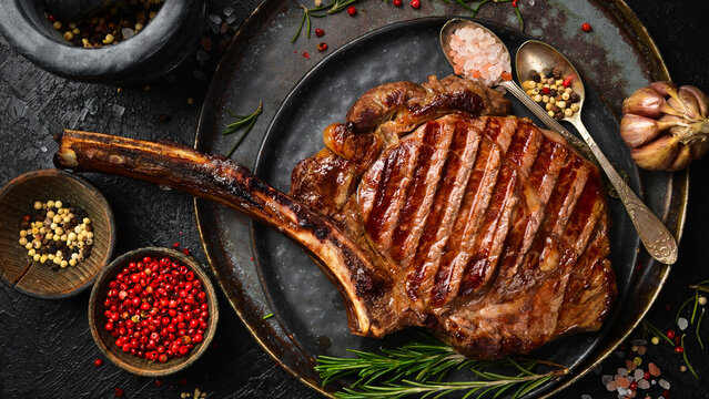 Tomahawk steak on the bone. Fried juicy steak on a plate. Top view.