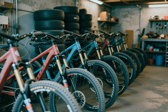 Wide angle view of mountain bikes standing in repair workshop, showcasing fleet maintenance, rental inventory, outdoor sports retail service. Ideal for cycling business marketing