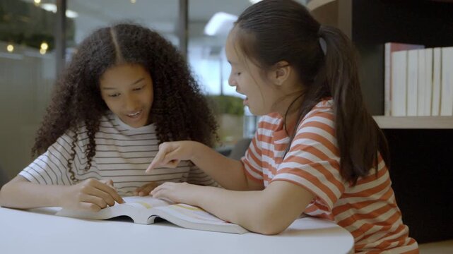 Two girls studying and sharing ideas in a library during afternoon