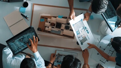 Obraz premium Top down view of manager pointing at house model and explain building design. Aerial view of architect engineer brainstorming about interior construction while tablet display house plan. Alimentation.