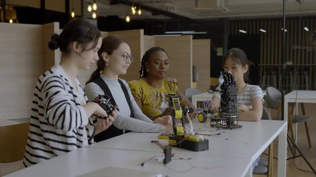 Four women work on robot parts in a lab setting while sharing ideas and learning together in a collaborative activity