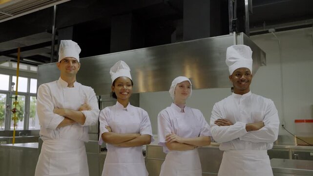Group of chefs poses in modern kitchen setting with smiles and uniforms