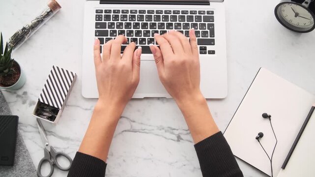 Hand taping on keyboard, woman working on laptop, top view, overhead shot, female hands typing, laptop keyboard, office work, home office, professional setting, 