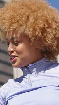 Vertical video: Laughing woman reacting to off camera comment on rooftop in lavender top and watch