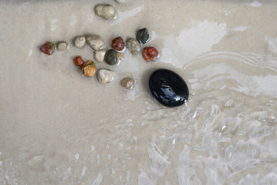 Spa stones on wet sand with gentle water ripples, minimal wellness background with copy space