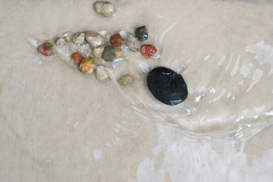 Black spa stone with water ripples on wet sand, zen wellness concept and natural background