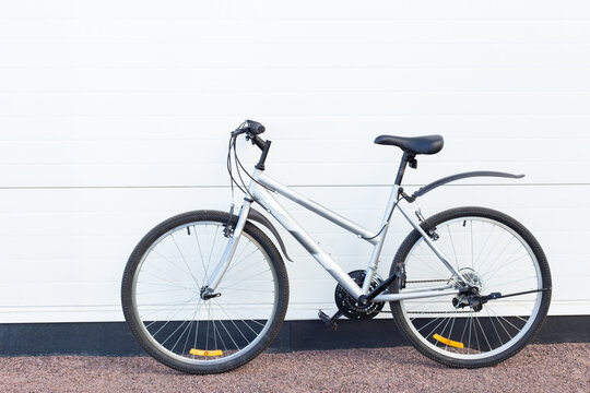 White bicycle parked against a clean wall outdoors, urban cycling, eco transport, active lifestyle, minimalist mobility concept.