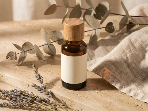 Small amber glass bottle with wooden cap on travertine with lavender in North America.