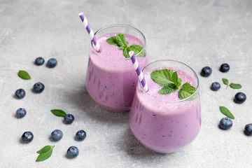 Tasty smoothie in glasses, fresh blueberries and mint on grey table, closeup © New Africa