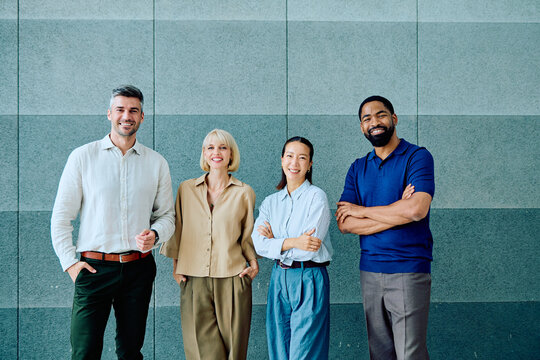 Four smiling multi-ethnic businesspeople posing in business casual attire, representing teamwork, unity, and professional collaboration