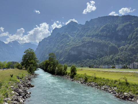 Turquoise Alpine River With Rocky Banks and Forested Mountain Peaks in the Glarus Valley of Switzerland