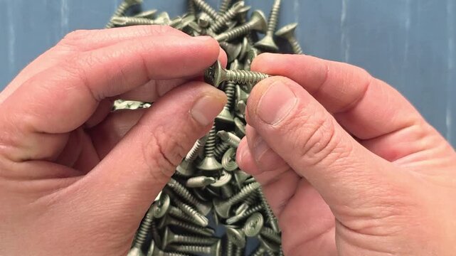 A person showing a self-drilling screw, a wood screw, and a self-piercing bugle-head screw&mdash;types commonly used in wood, flat head
