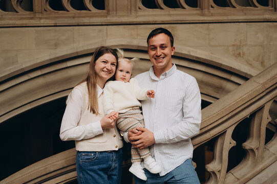 A family portrait of parents with their child against the backdrop of the building's architectural elements.