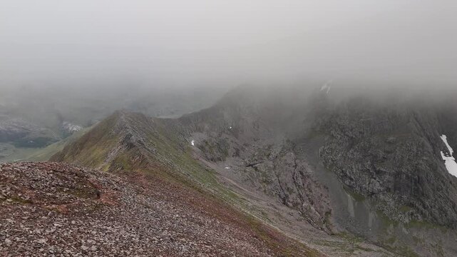 Aerial drone push forward of a hiker walking on the CMD route to Ben Nevis in Scotland.