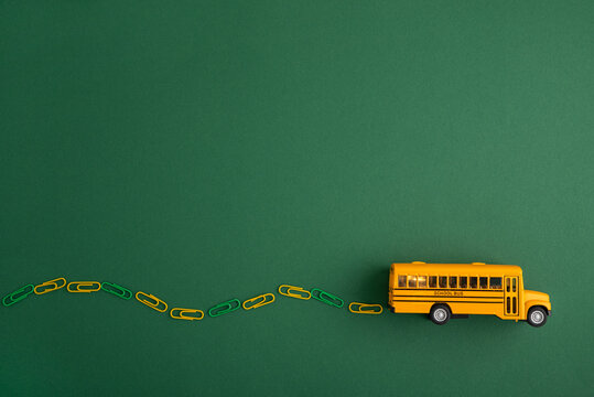 Yellow school bus driving along paperclip road