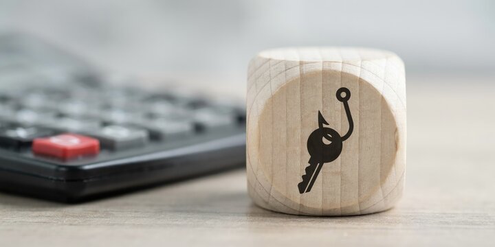 Wooden die with key and fishing hook next to a calculator