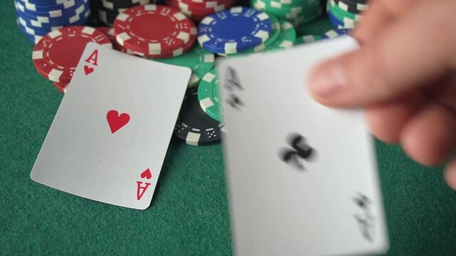 A hand shows three aces playing cards on a green felt table with colorful poker chips creating an exciting gaming atmosphere